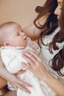 Mutter hält Neugeborenes im weißen Kleidchen – Babyshooting Frankfurt Rhein-Main